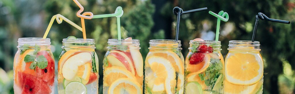 Diversos copos com sucos de frutas naturais e canudos