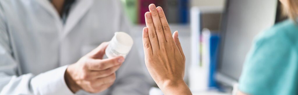 Pessoa recusando comprimidos de um médico com a mão