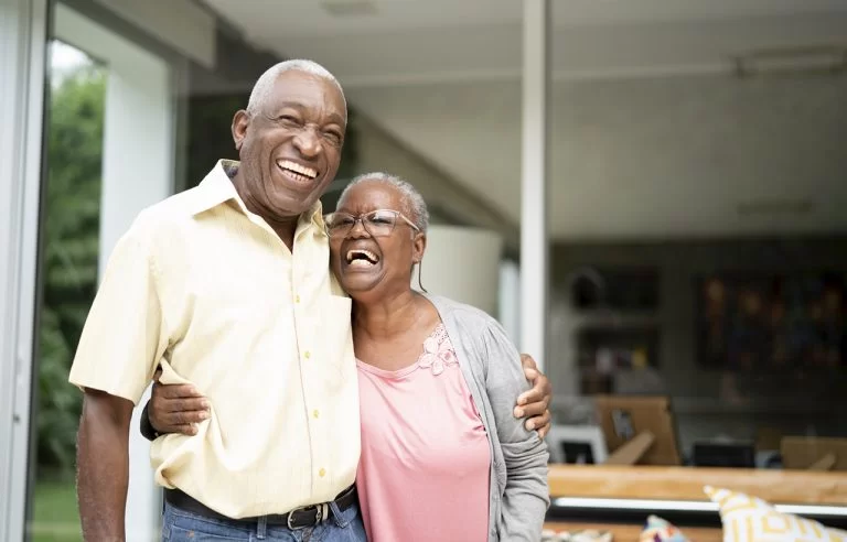 Casal de idosos negros abraçados e felizes: felicidade na terceira idade