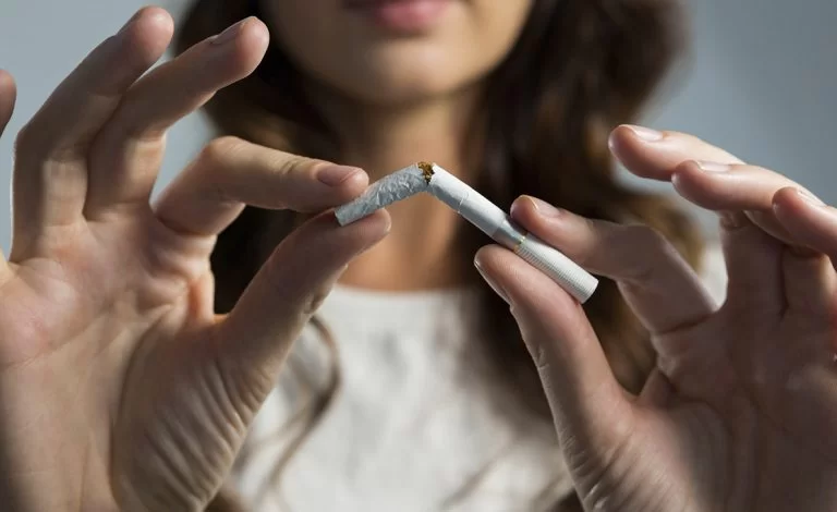 Antitabagismo: mulher cortando cigarro ao meio para simbolizar que parou de fumar