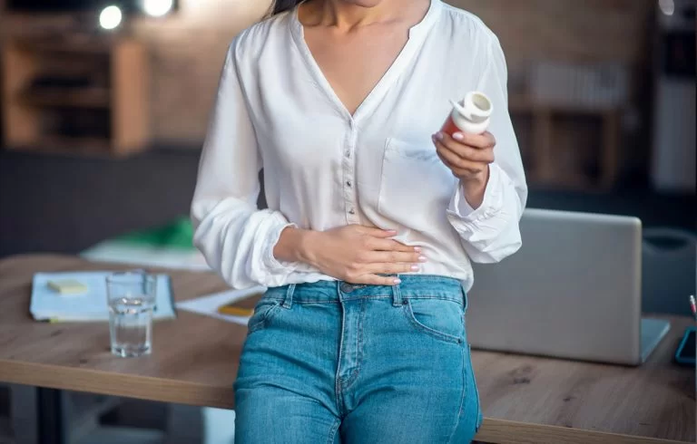Mulher com mão na barriga e outra com um iogurte simbolizando que está com prisão de ventre