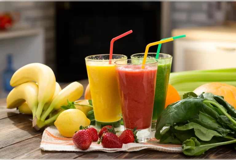 Alimentos saudáveis: 3 sucos de frutas naturais, banana,morango e verduras em cima da mesa