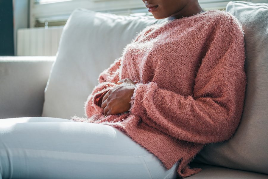 Mulher com as mãos na barriga sofrendo com constipação